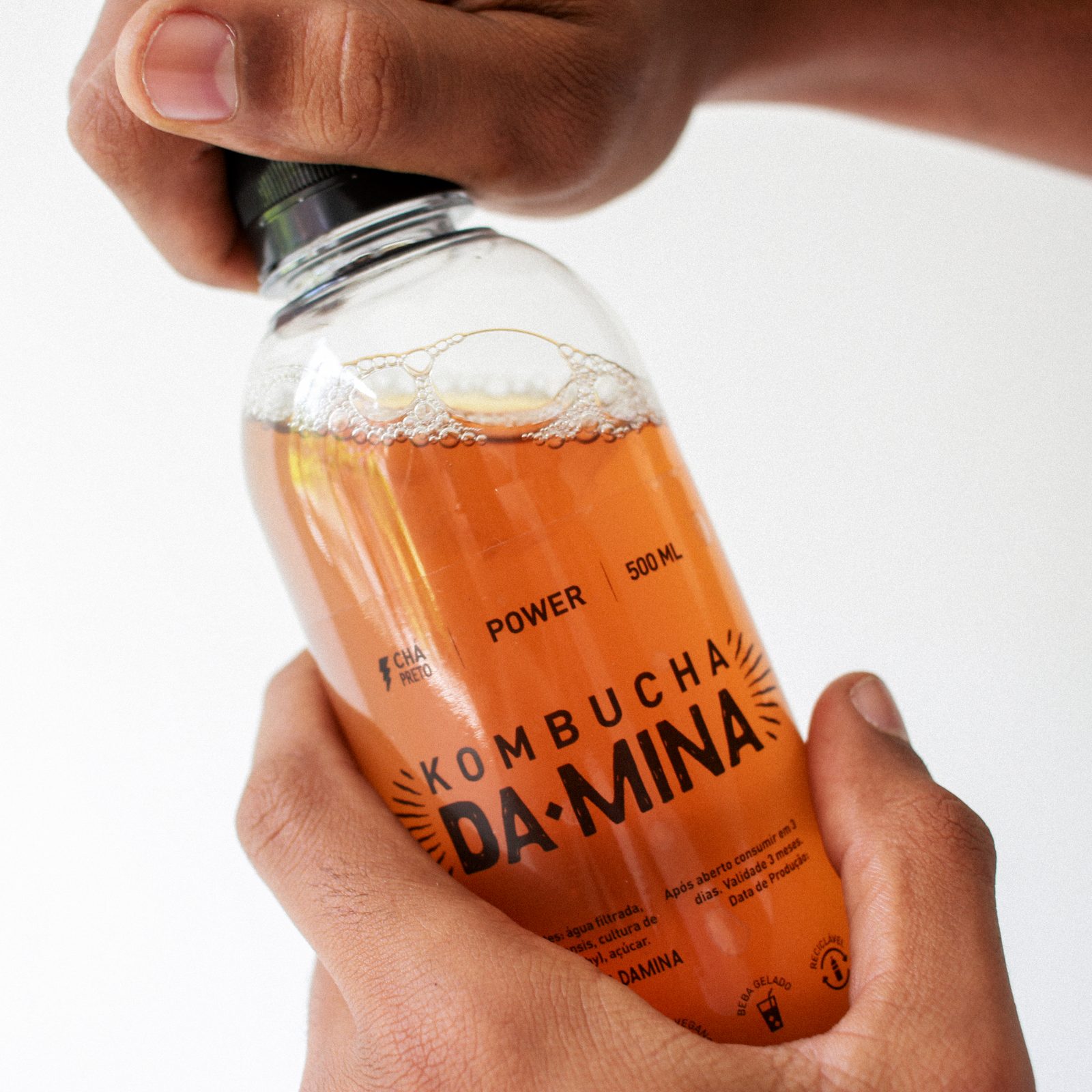 Garrafa de Kombucha da Mina sendo segurada nas mãos